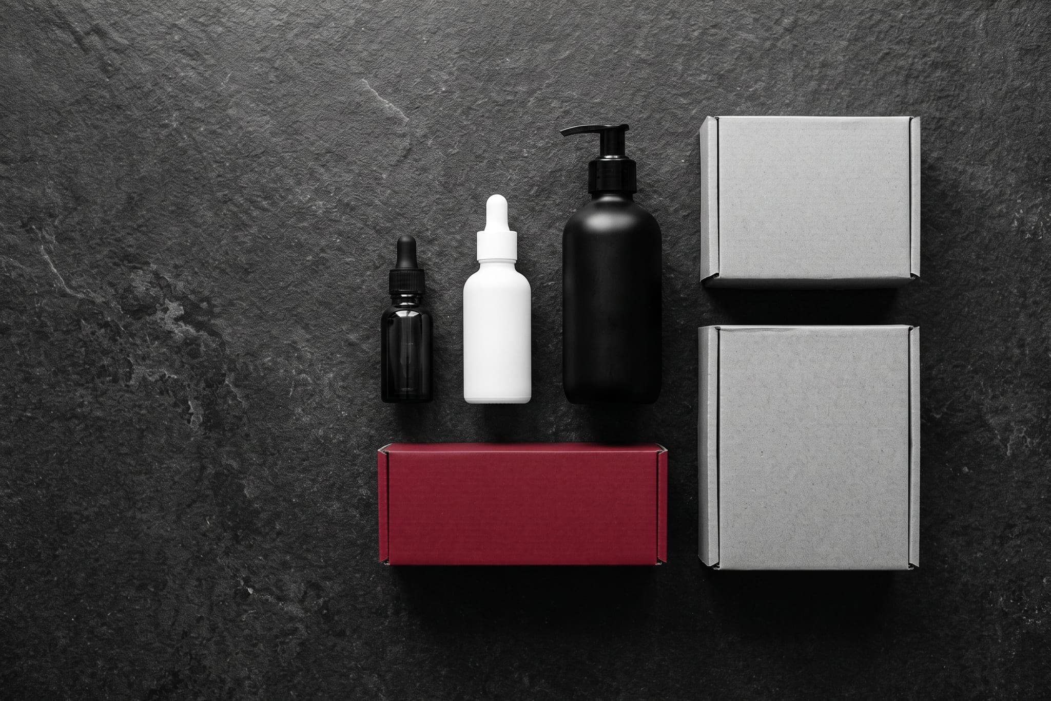 Cosmetic bottles and shipping boxes from above, one box crimson