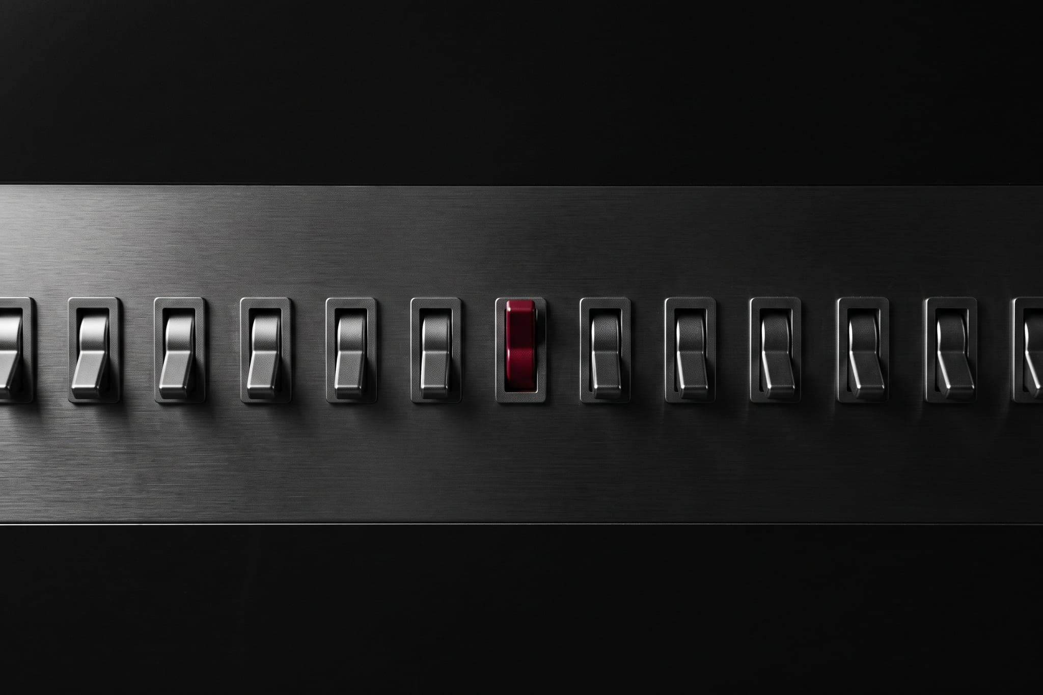A row of identical switches all off, exactly one on and crimson