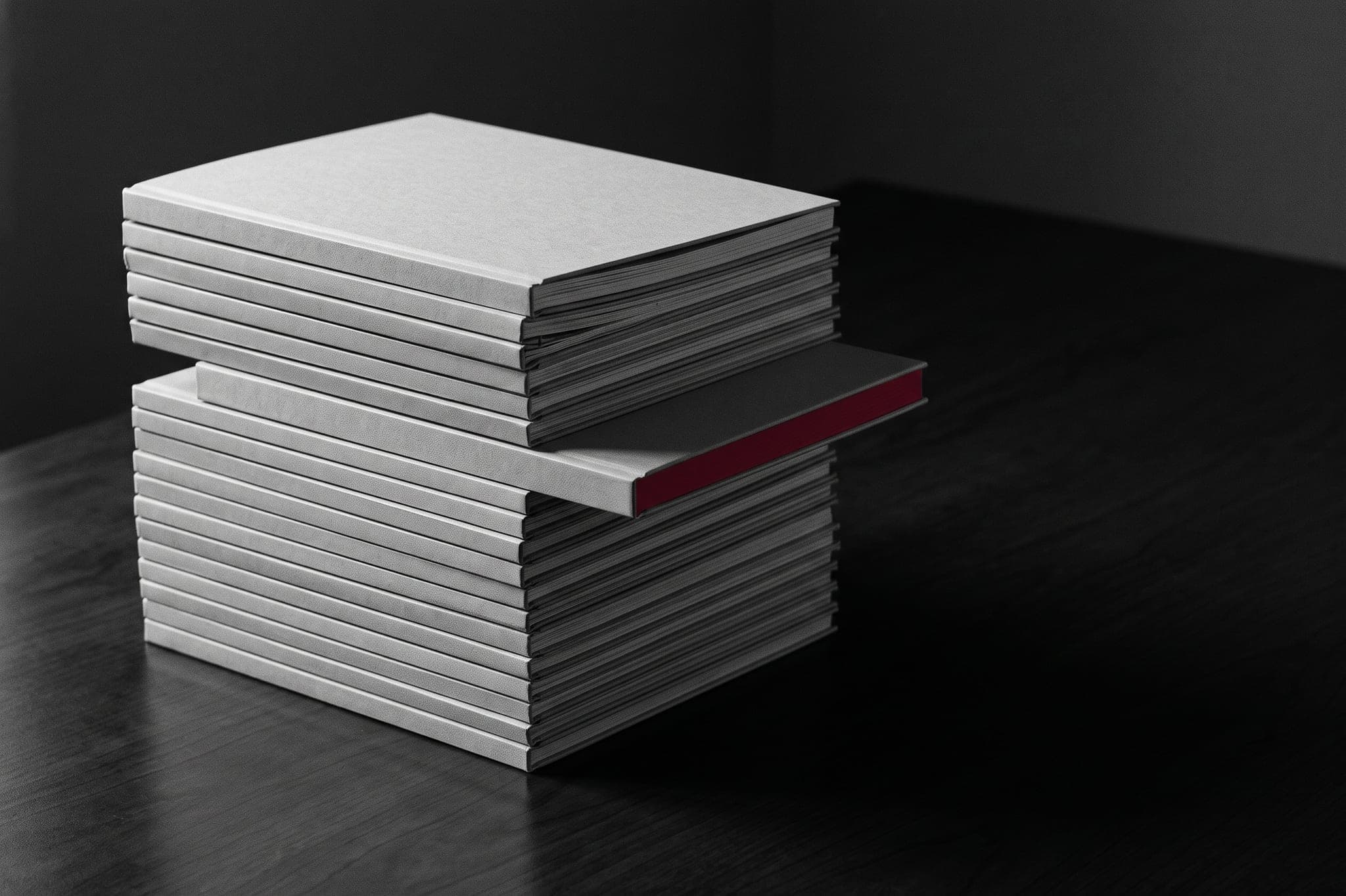 A stack of blank-cover reports, one pulled out with a crimson edge