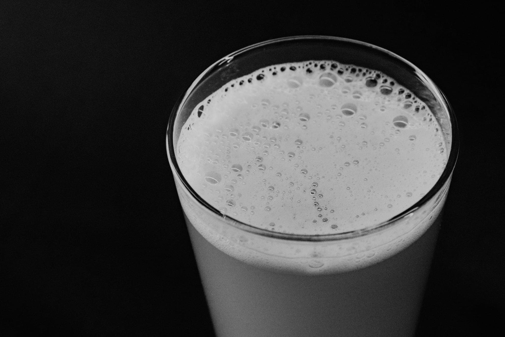 A glass of beer with a head of foam, seen from above against a dark background