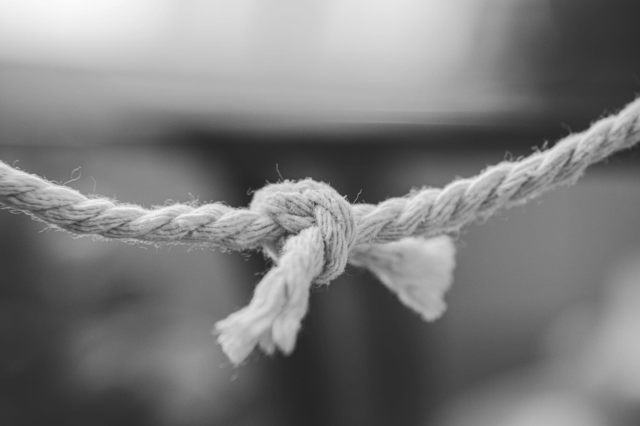 A rope with a simple knot tied in it, its frayed end hanging down