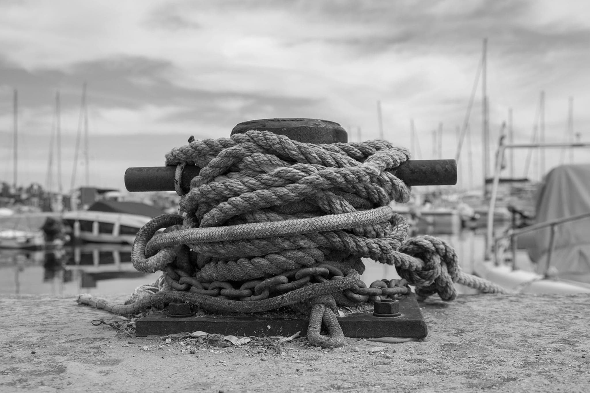 Mooring ropes of several different thicknesses wound many times around a single iron bollard on a quay