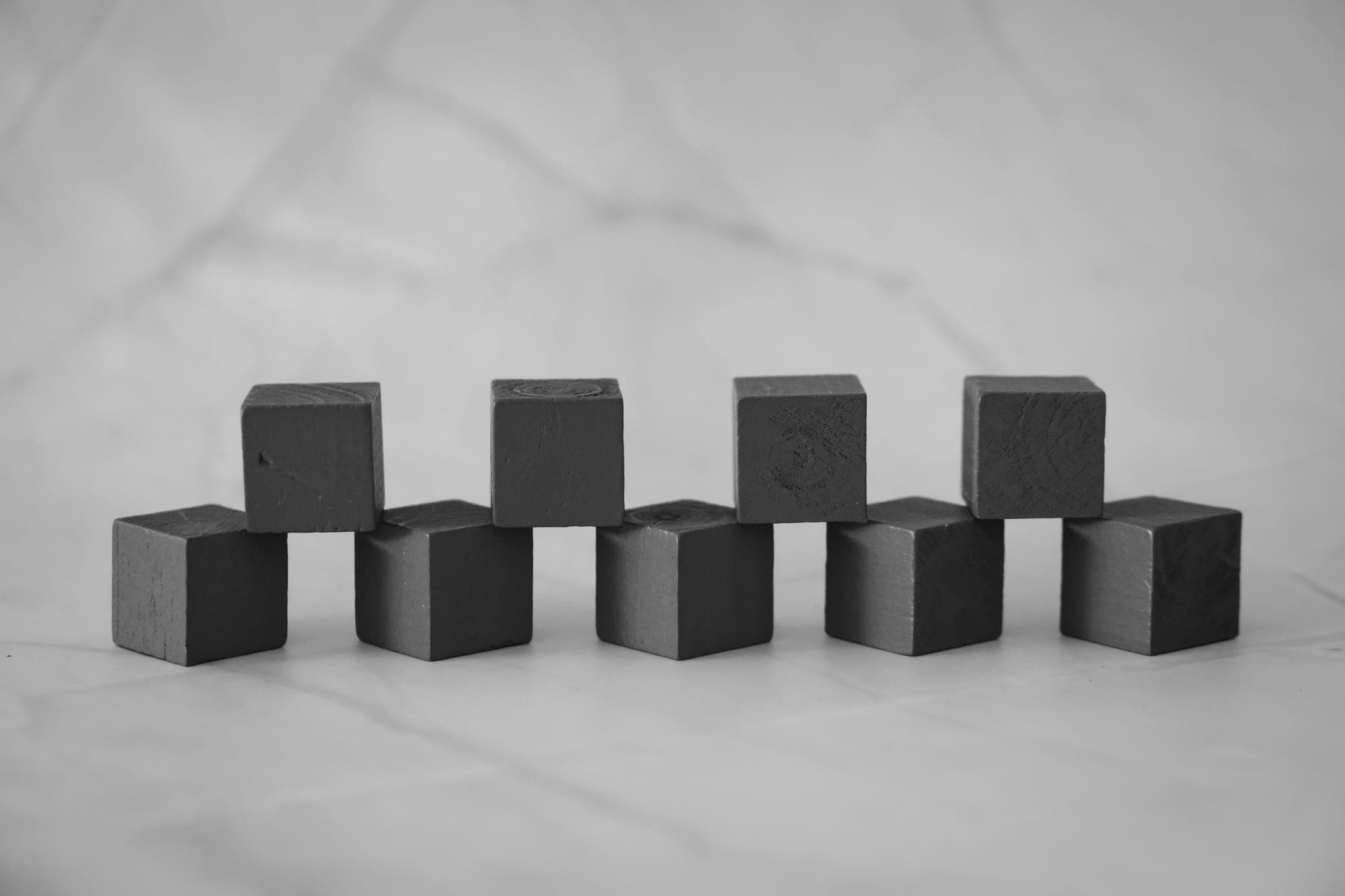 Nine wooden blocks in two staggered rows on a marble surface