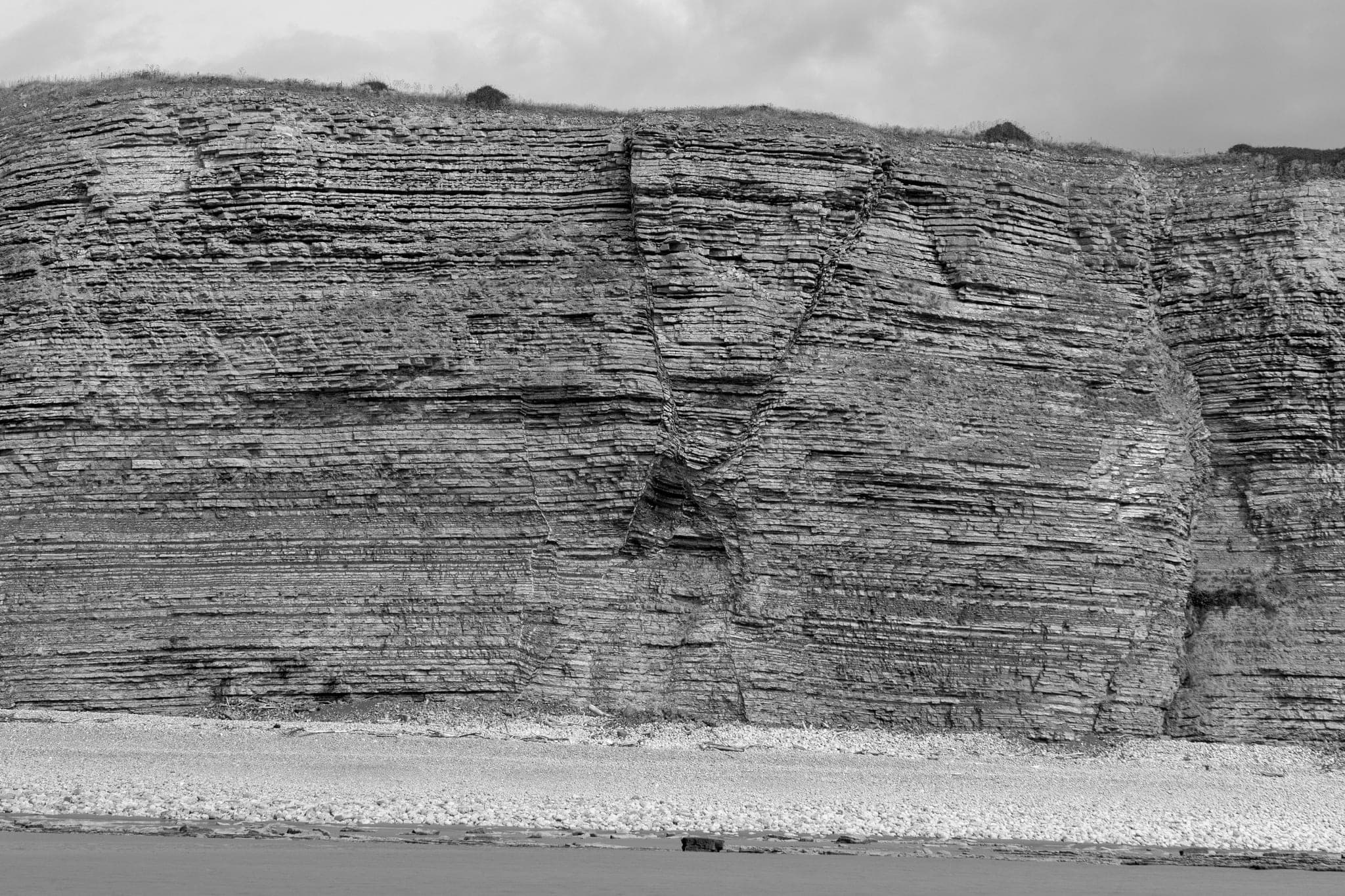 A coastal cliff face showing distinct sedimentary layers stacked on each other