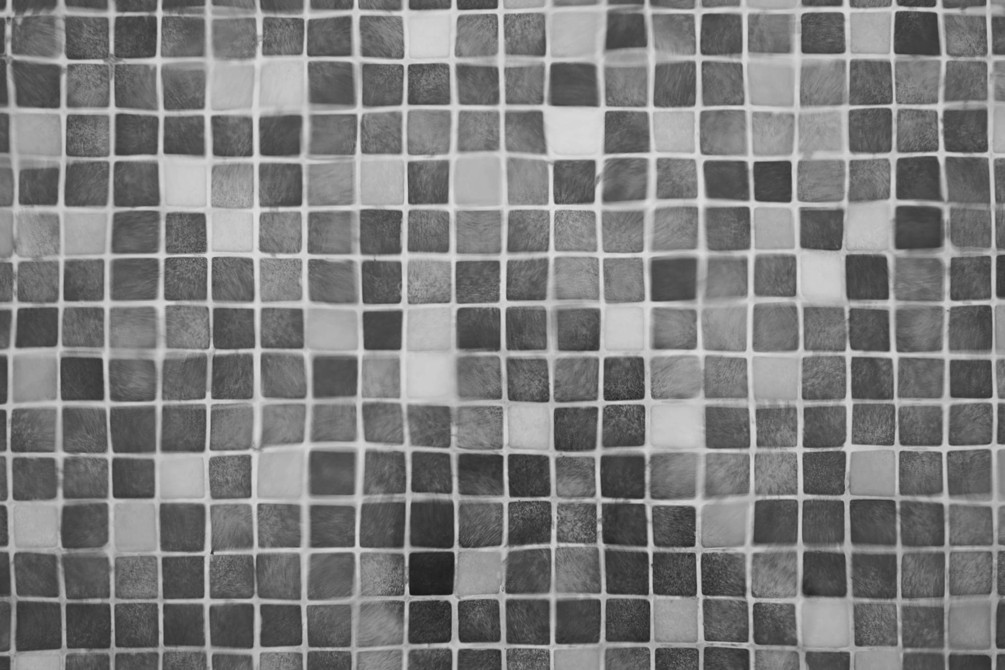 Square mosaic tiles in many shades of grey, set in a regular grid.