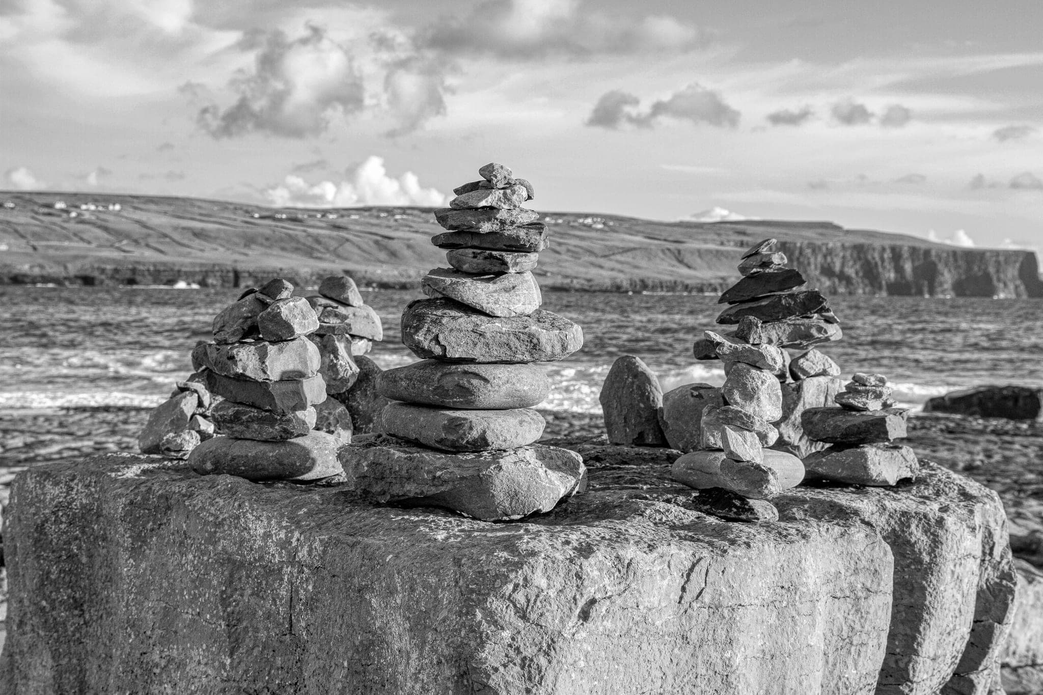 Stacks of balanced stones on a large rock by the sea