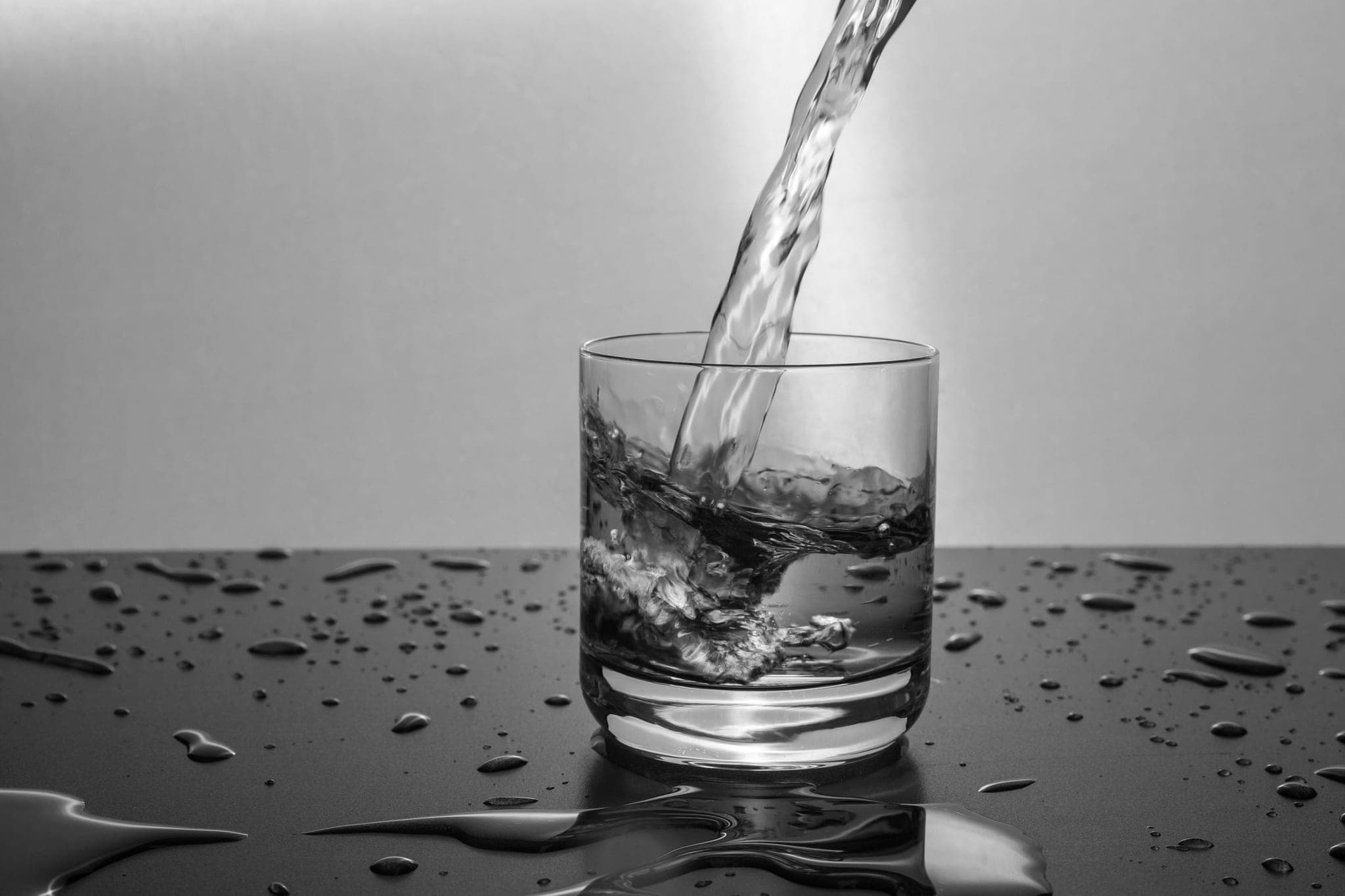 Nước được rót vào một chiếc cốc trên mặt bàn tối lấm tấm giọt nước