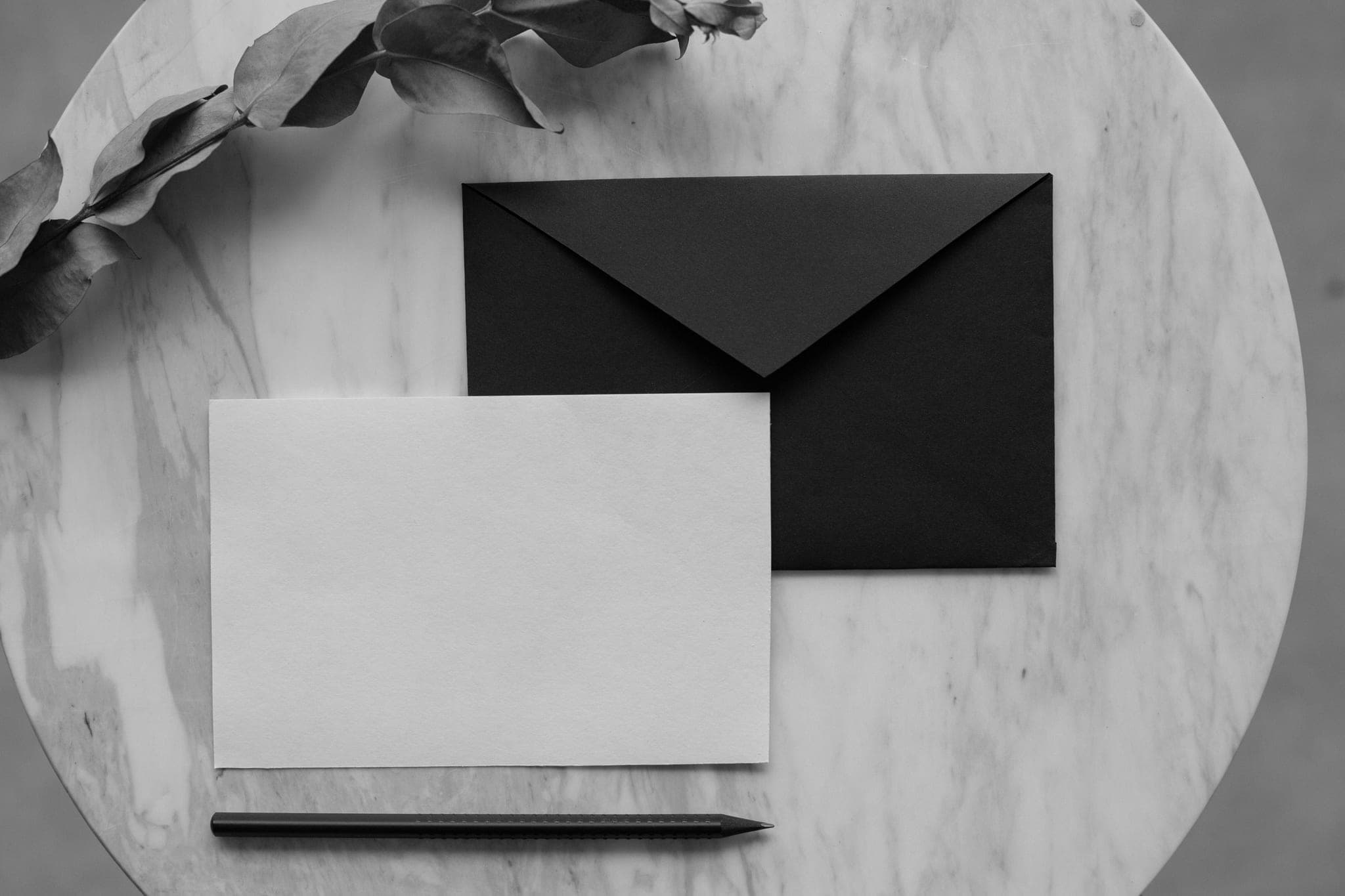 A black envelope and a blank white card on a marble table