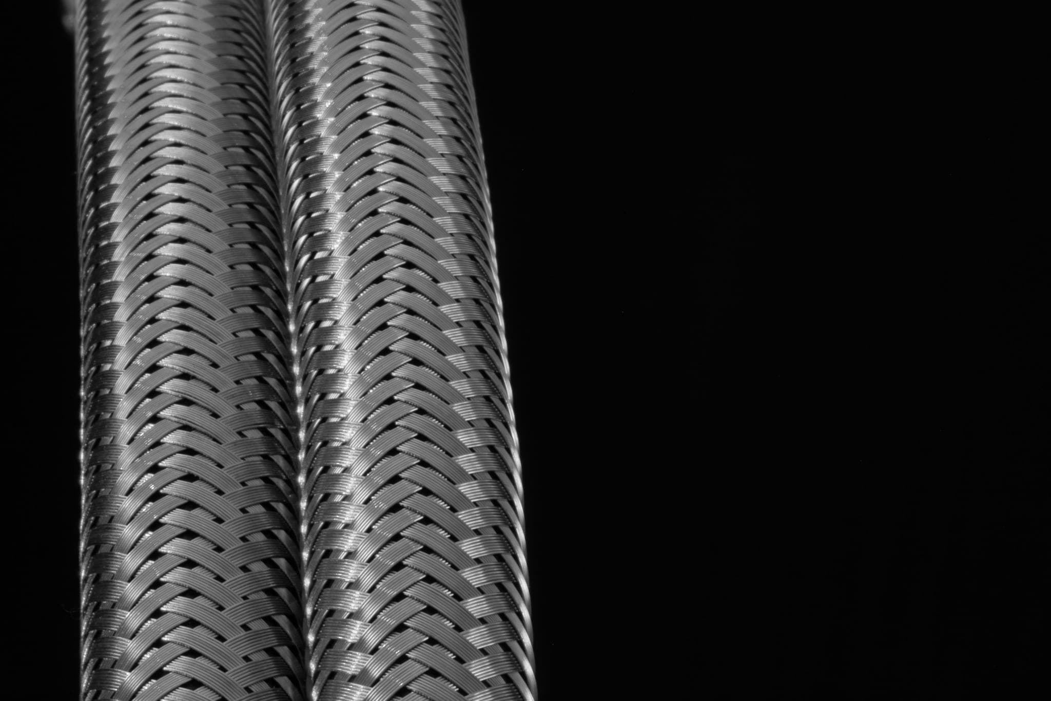 Braided metal hoses running side by side, each on its own path
