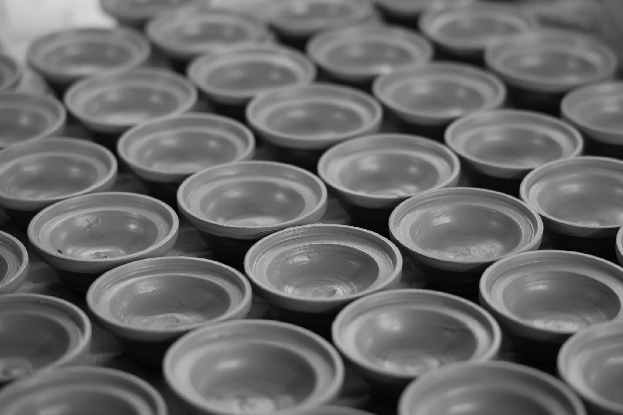 Rows of near-identical unglazed clay bowls, lined up edge to edge