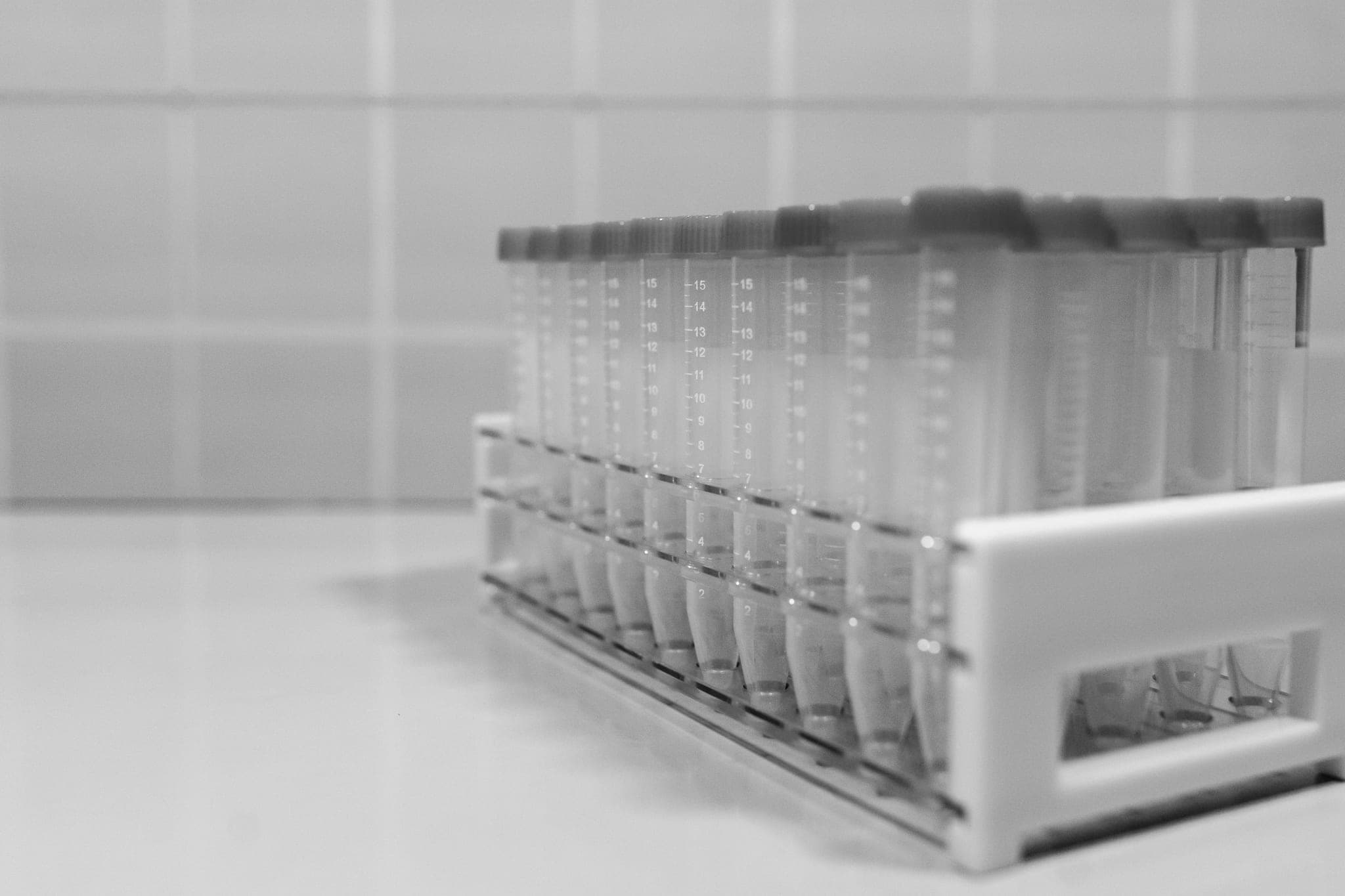 A rack of empty test tubes with printed volume marks, on a pale bench