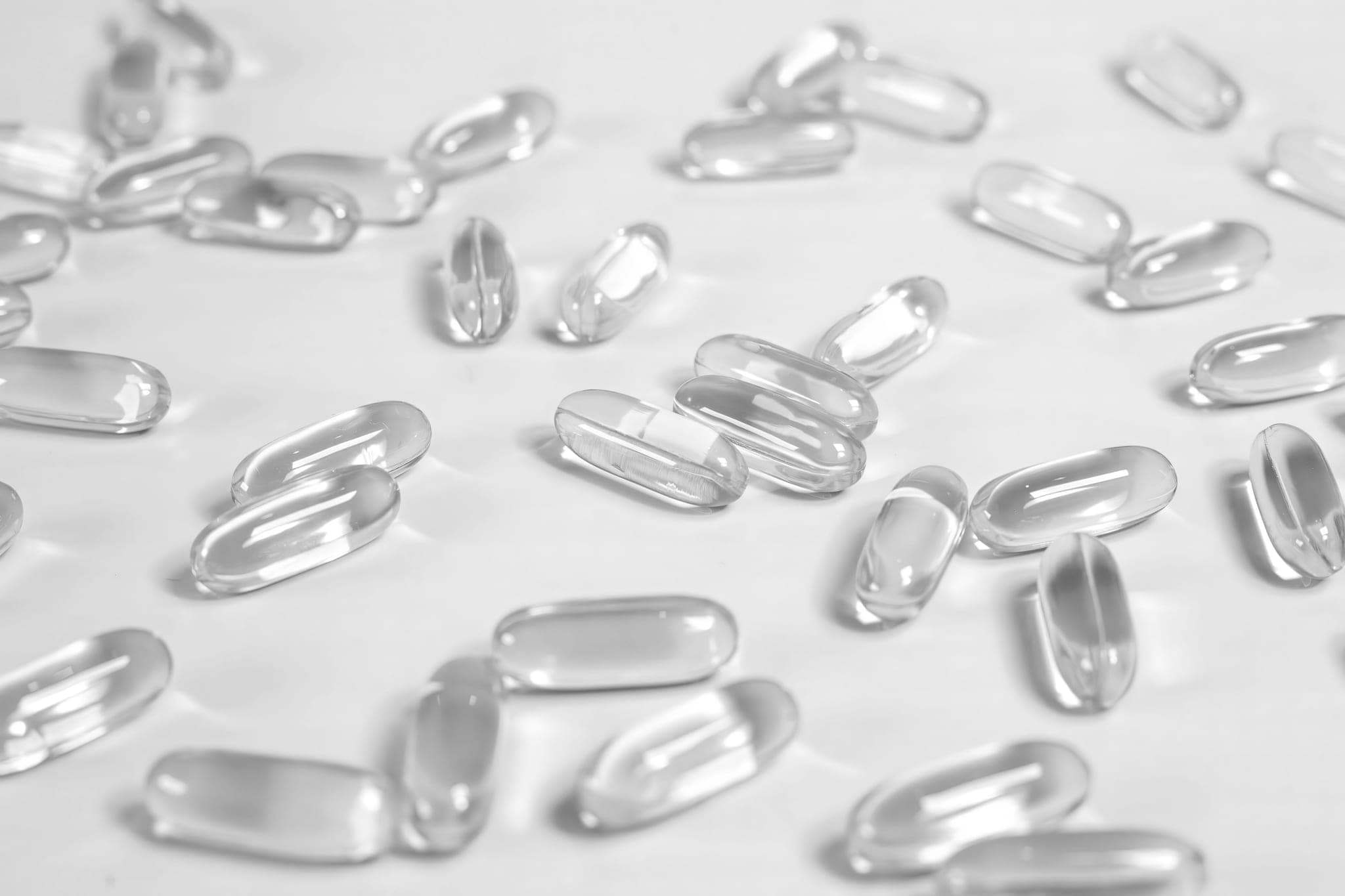 Clear softgel capsules scattered across a pale surface