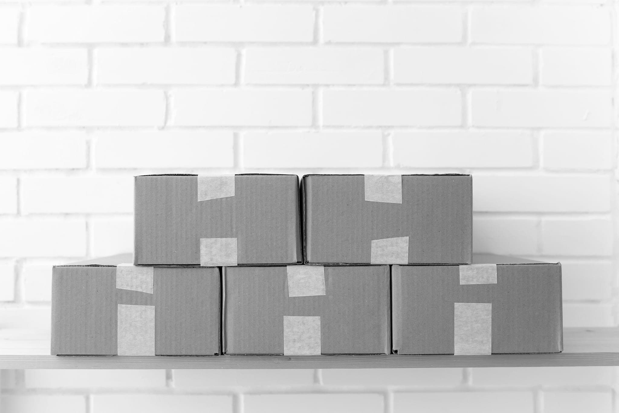 Taped cardboard boxes stacked neatly on a wooden shelf